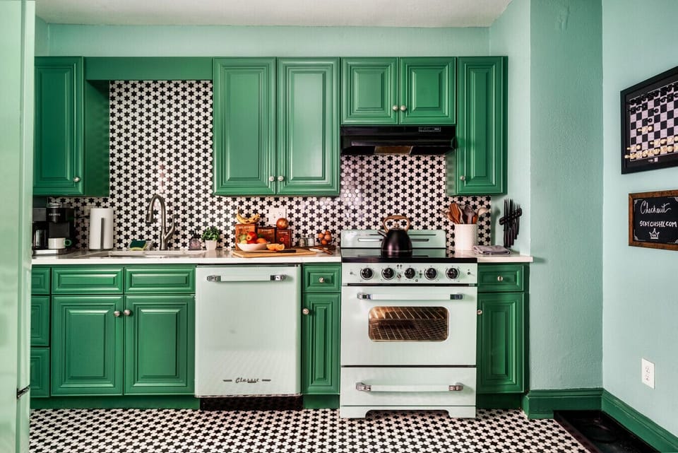 Step into a retro-inspired kitchen with vibrant green cabinetry, a charming vintage-style oven, and striking black-and-white star-patterned tile flooring