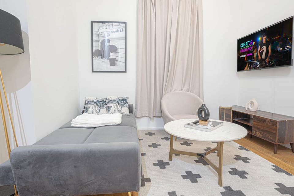 Futon setup facing smart TV with stylish décor, cozy ambiance and extra seating for movie nights.