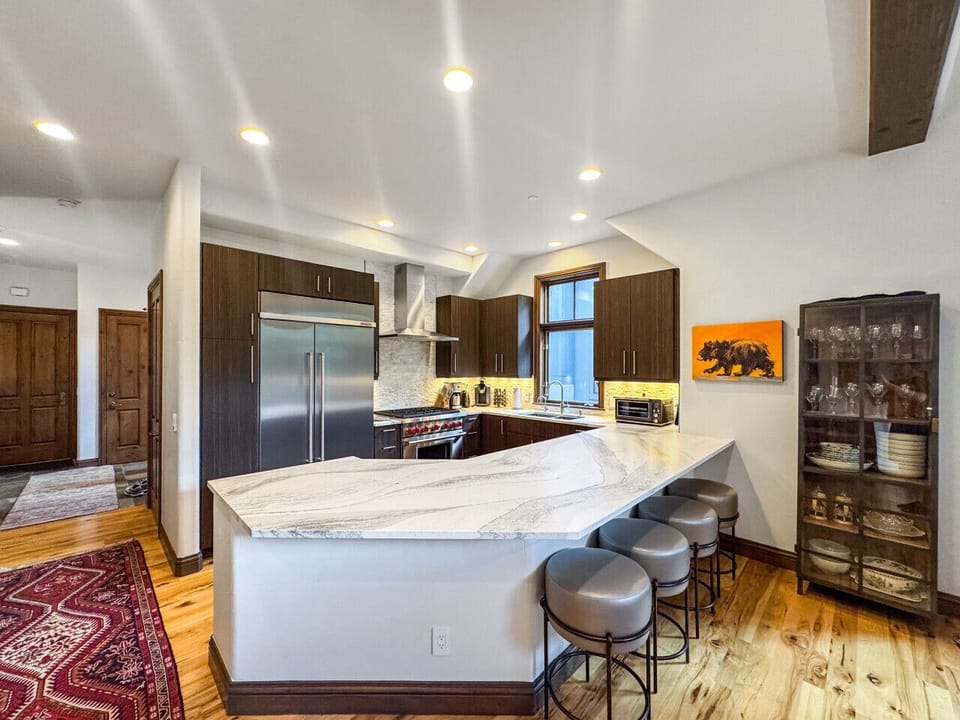 From this angle, admire the expansive quartz countertop island overlooking your chef`s kitchen. Every professional appliance and tool awaits to transform fresh ingredients into gourmet masterpieces. Culinary dreams come alive in your Arrowhead penthouse