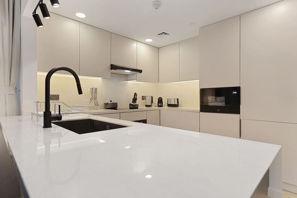 Sleek modern kitchen with matte beige cabinetry and black fixtures.
