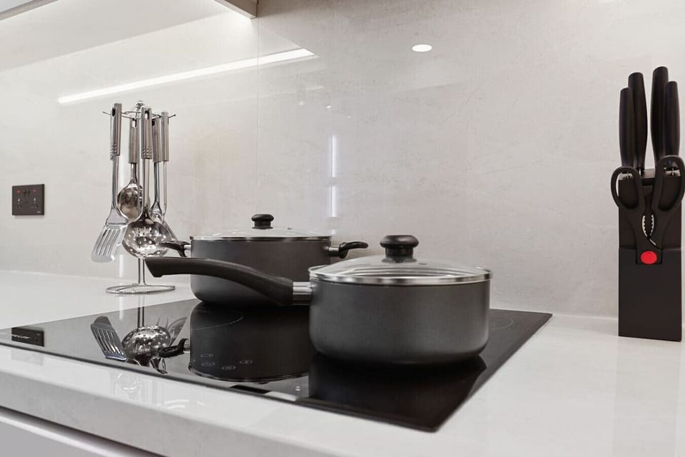 Sleek induction hob, stone backsplash, and essential cooking tools.