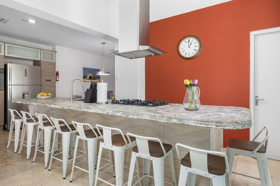Gather around this spacious kitchen island with your group, where modern appliances and a vibrant accent wall create the perfect backdrop for shared meals and morning coffee.