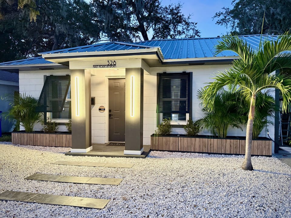 Newly remodeled front with white shells, planters and porch.  Two parking spaces