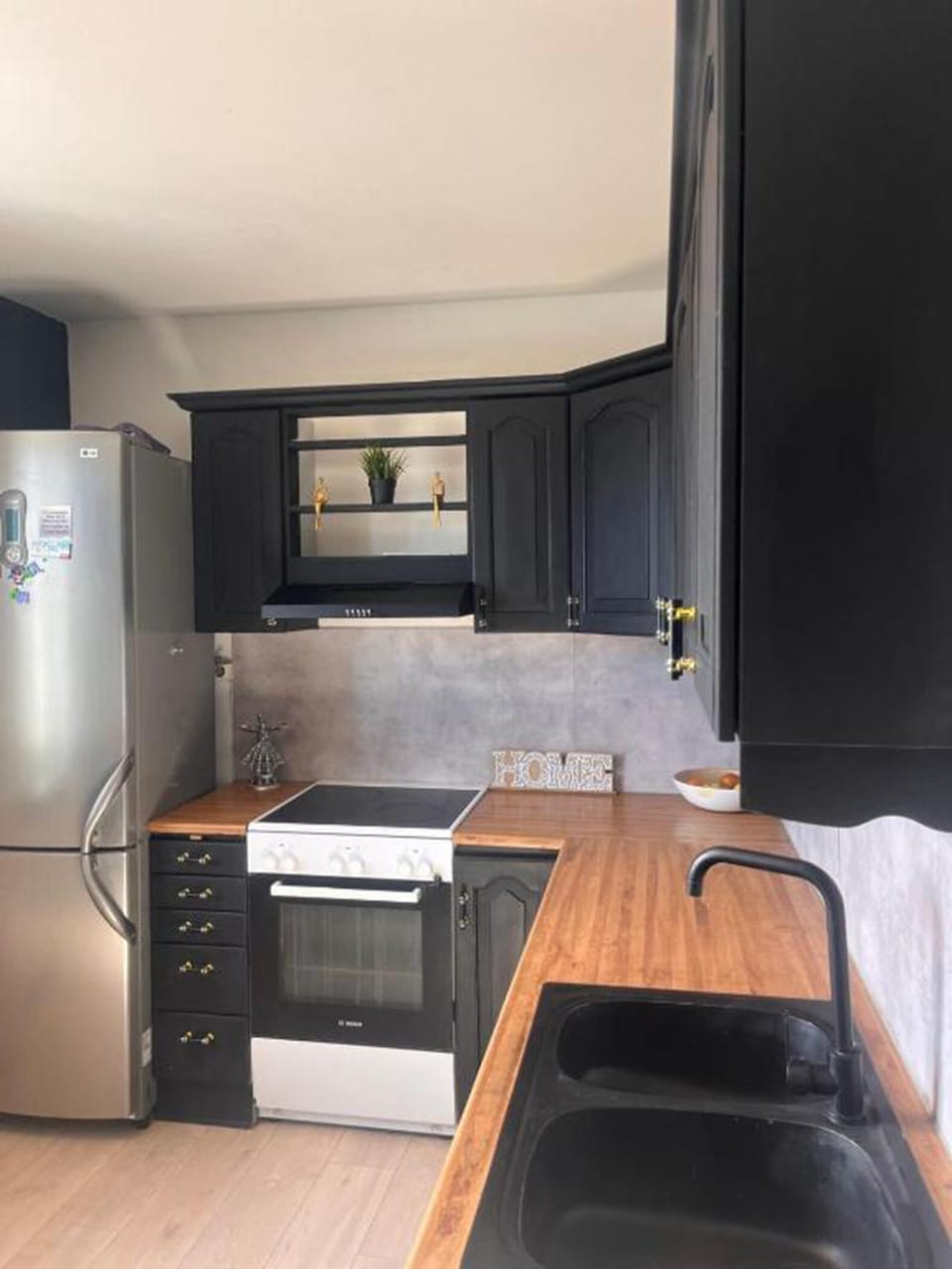 Kitchen with refrigerator, microwave, electric kettle, & appliances for cooking.