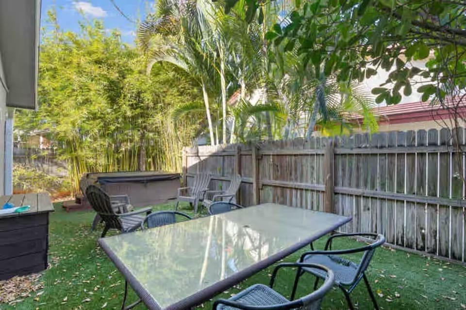Fenced in private backyard with hot tub, dining table and mutiple seating areas