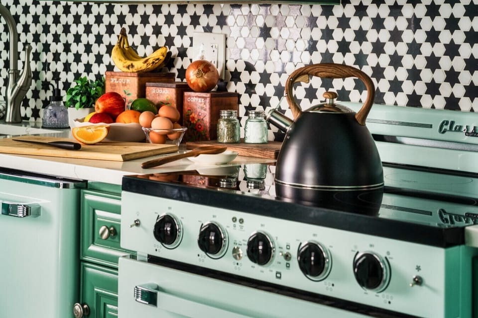 Step back in time with this charming mint green kitchen, complete with retro appliances and a classic black-and-white checkered floor.