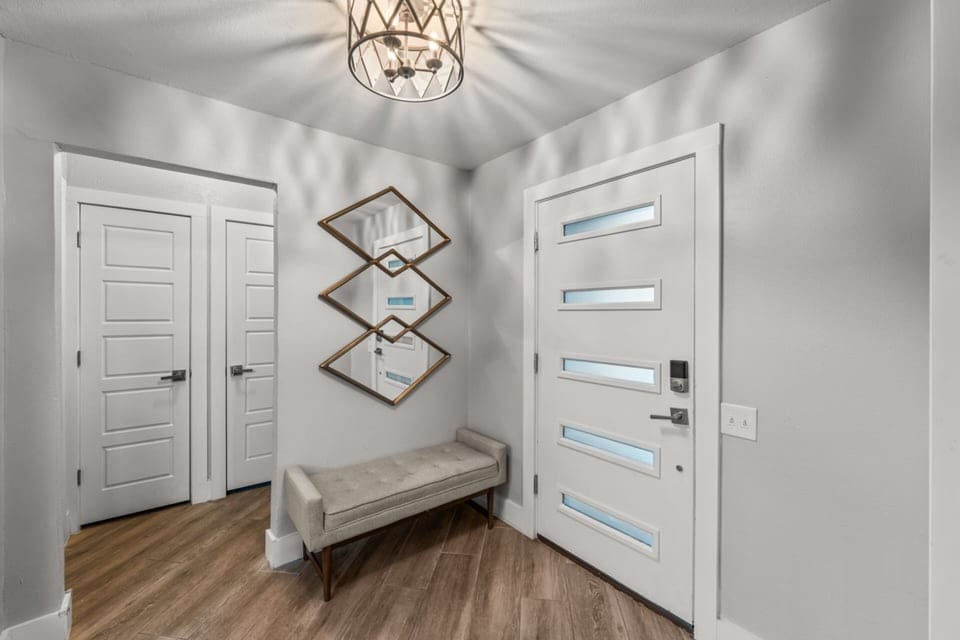 A clean, modern entryway with a bench and statement mirror offers a welcoming first impression as you step inside.