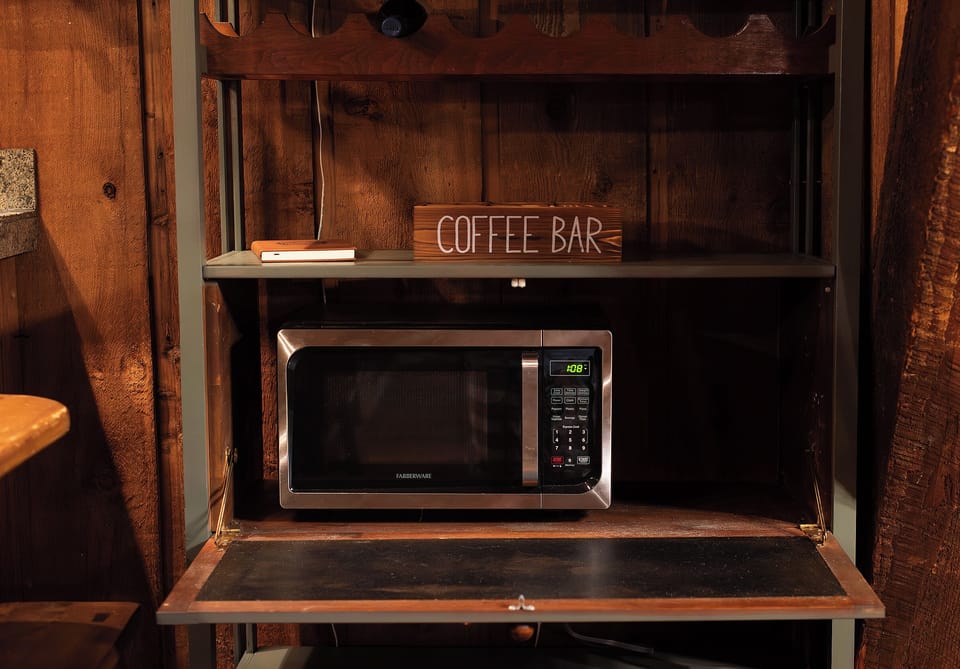 Microwave just below the coffee bar inside the cabinet.