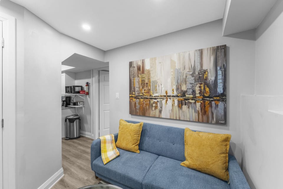Step into the cozy living room with its modern art and comfy sofa. The open layout leads seamlessly to the fully stocked kitchen, creating a bright and inviting space for relaxing and entertaining.