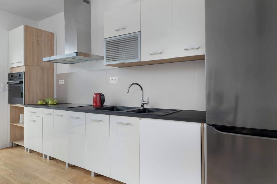 Functional, fully equipped kitchen with glossy white cabinets.