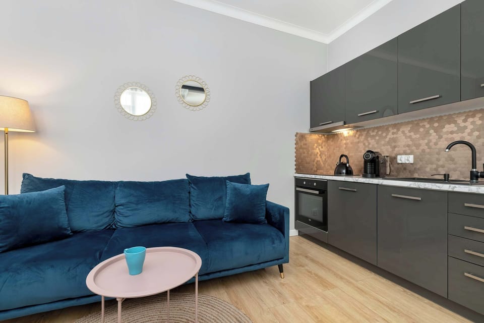 A modern living room with two deep-blue sofas, a round rug, and a TV mounted on the wall. The space feels both stylish and cozy.