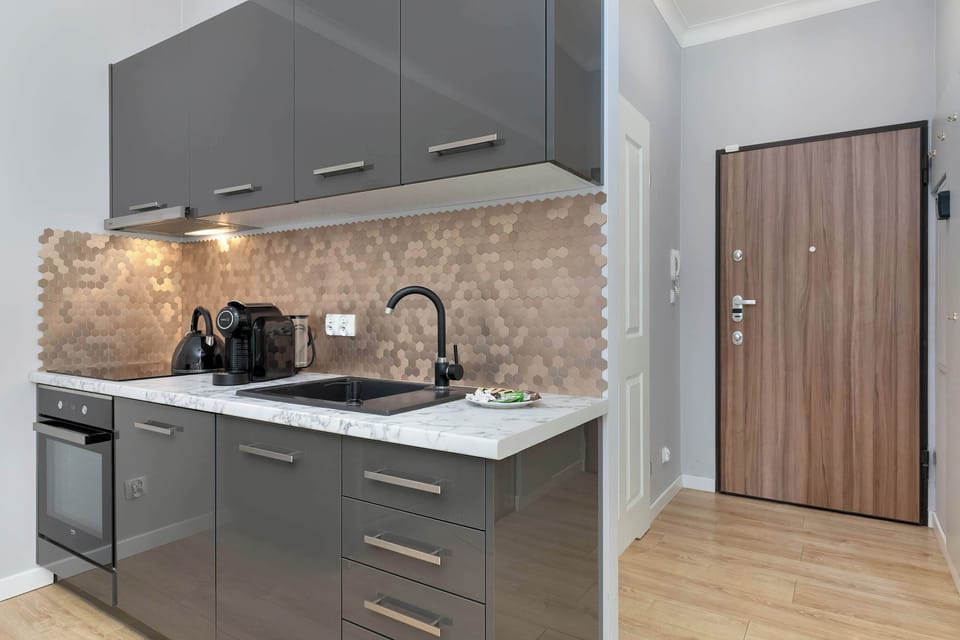 A sleek gray kitchen with modern appliances, backsplash, and cabinets. Wooden details soften the look.
