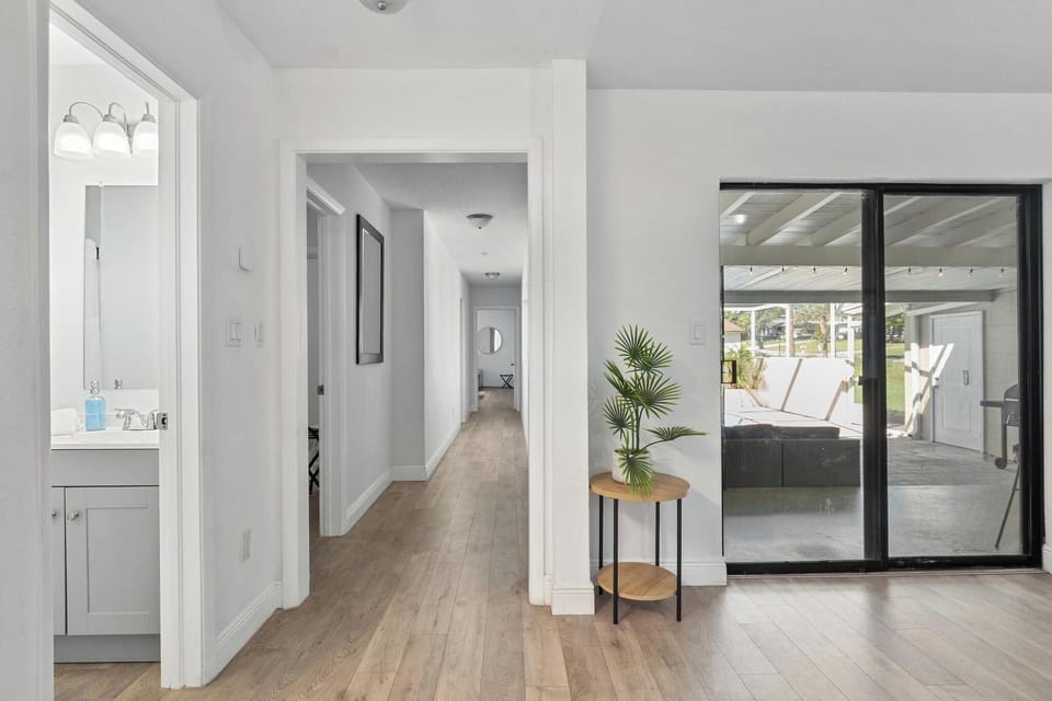 Bright hallway leading to spacious bedrooms and pool access. Features modern wood flooring, neutral tones, and natural light—creating a seamless flow between indoor comfort and outdoor relaxation.