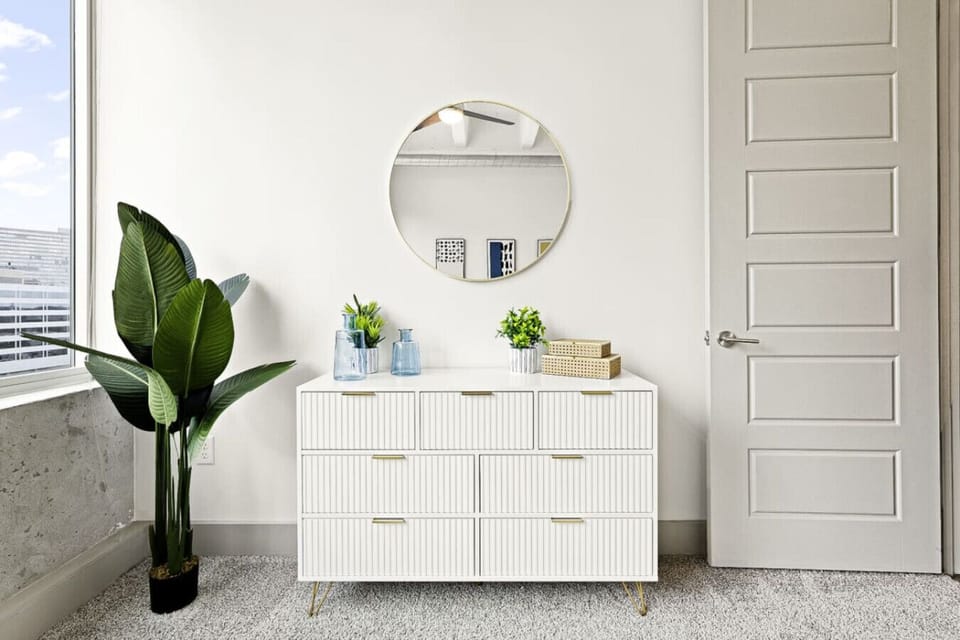 Stylish dresser and greenery create a bright, inviting space with city views!