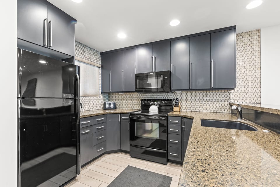 Snow Flower 126 offers a well equipped kitchen with grey cabinets, granite countertops, and tiled backsplash.