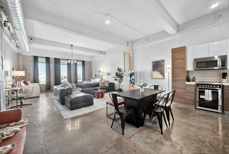 Open Loft Living – Spacious design blending dining, lounge, and kitchen with industrial-chic vibes.