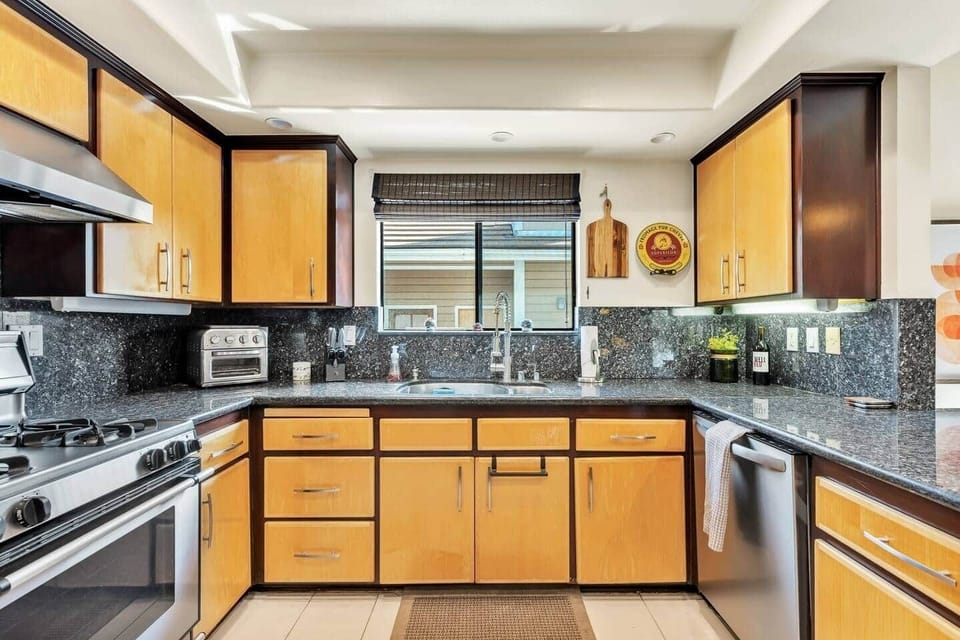 Stylish kitchen with granite counters, stainless appliances, and two-tone cabinets.