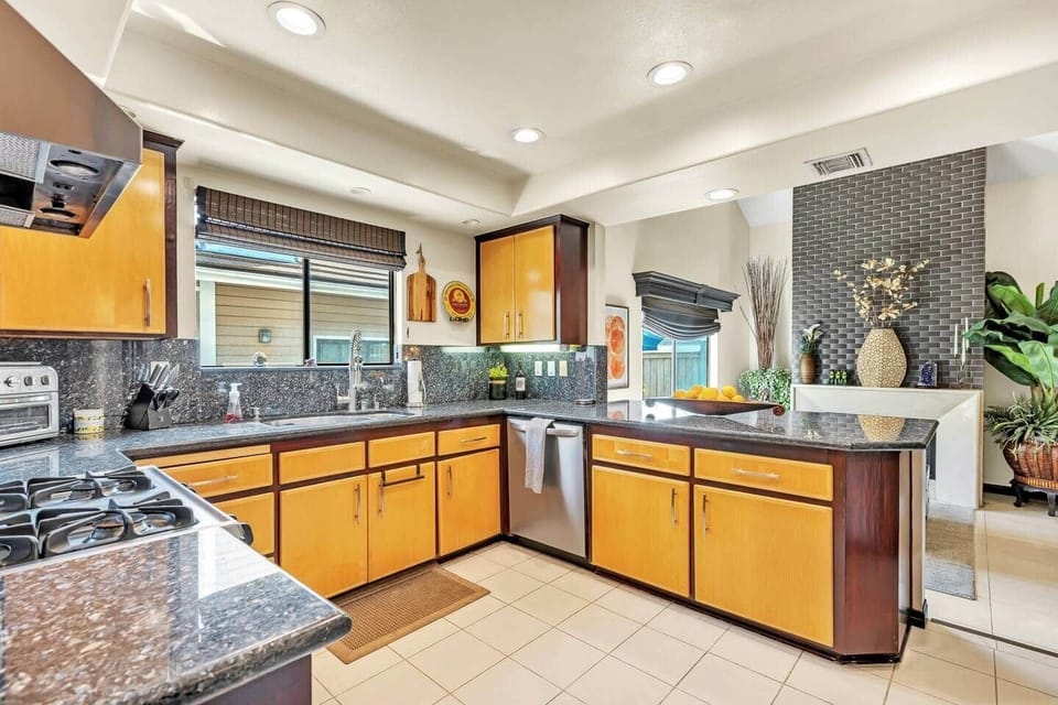Open-concept kitchen with granite island, gas range, and modern lighting.