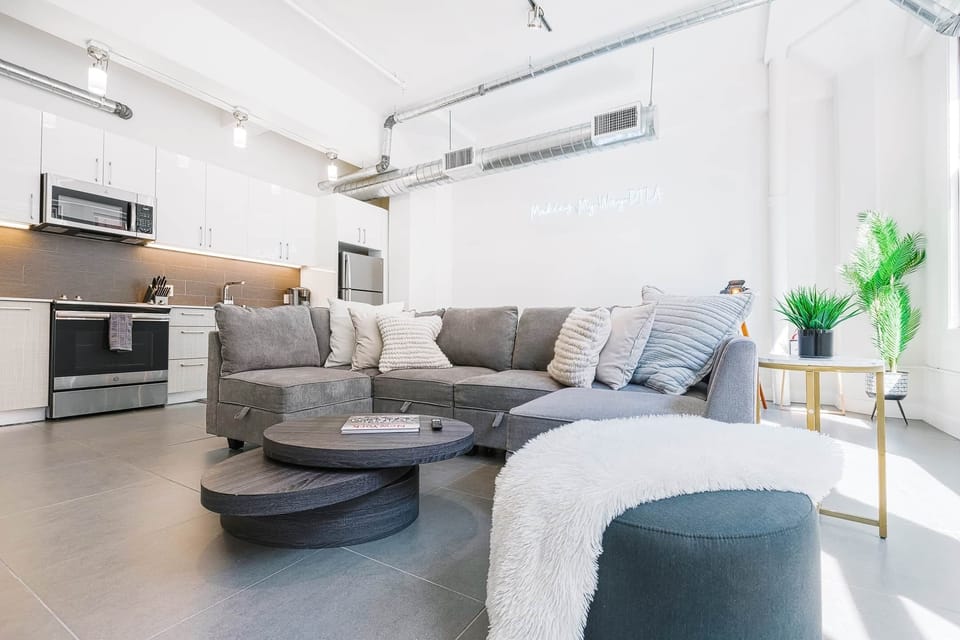 Airy living room with natural light, cozy seating, and a large TV for relaxing.