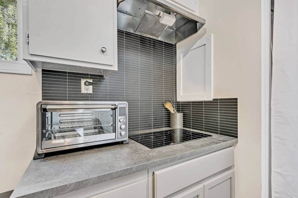 Compact kitchen setup with cooktop, toaster oven, and modern backsplash.