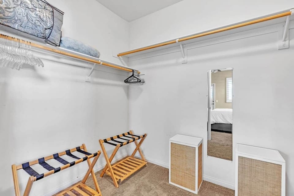Spacious walk-in closet with hanging space, luggage racks, and mirror.