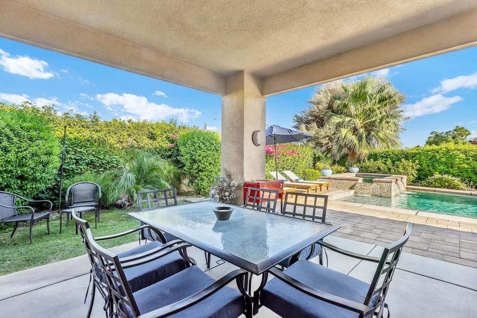 Covered patio with dining area and views of the private pool and greenery.
