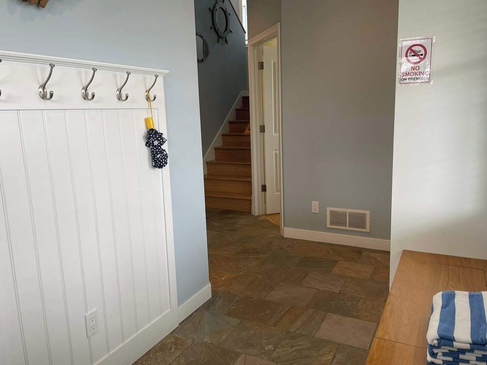 Mudroom area with bench and hooks at the front door entry.  A bedroom, bathroom, and garage entrance is on the ground floor. 