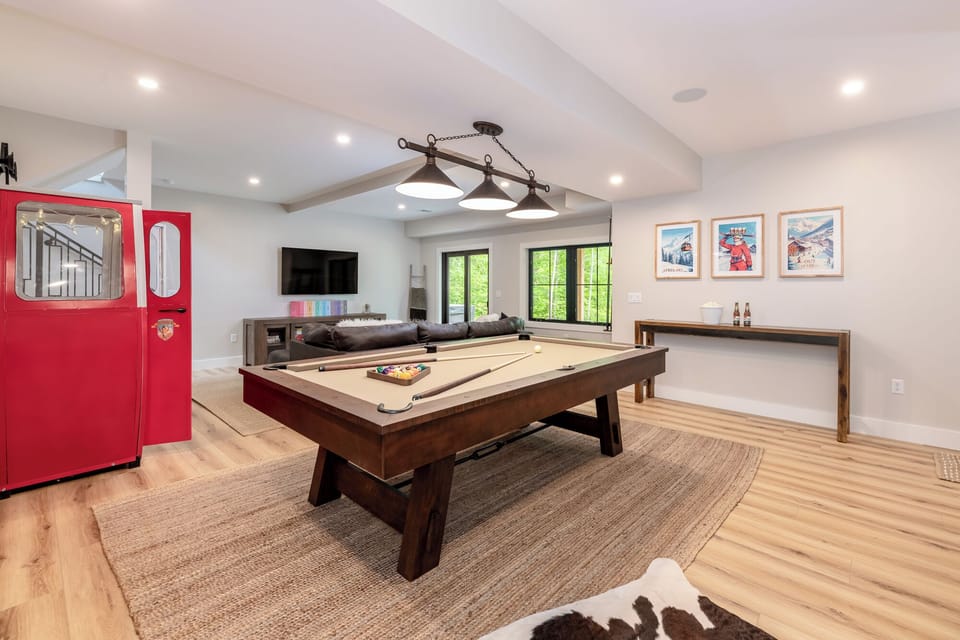 Spacious game room with a pool table, cozy seating area, and large TV. Perfect for family fun or relaxing evenings, with plenty of space to gather and enjoy time together.