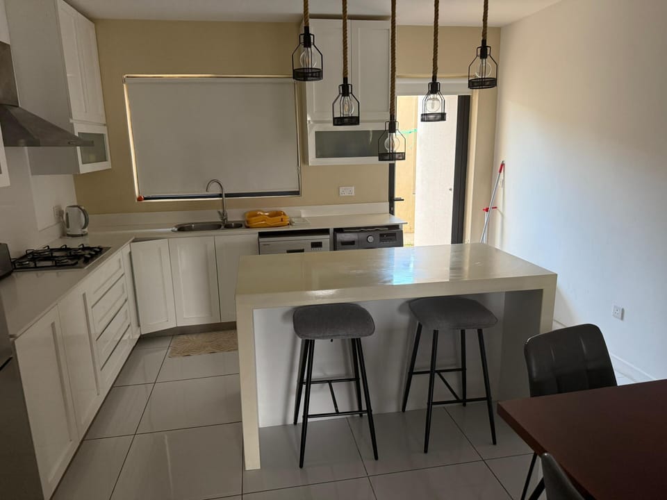 full kitchen, two stool dining space pictured, and main entrance 