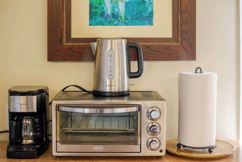 Convenient kitchen setup with a coffee maker, toaster oven, and kettle for easy breakfasts and snacks.