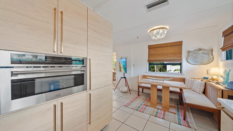 This modern kitchen features sleek built-in appliances and flows seamlessly into a cozy breakfast nook with chic coastal décor.