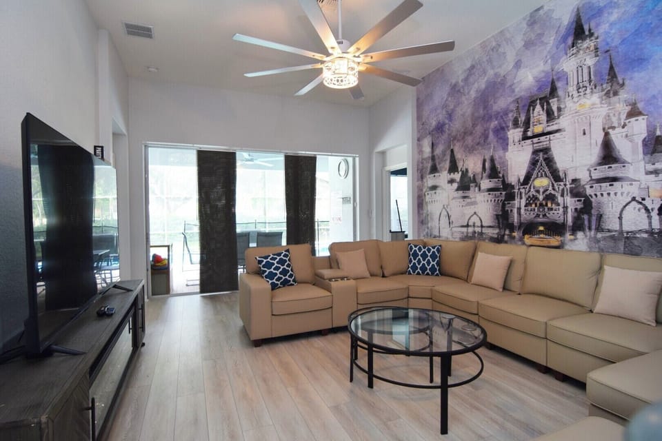 Stylish living area with L-shaped sofa, Smart TV, sliding doors to pool deck