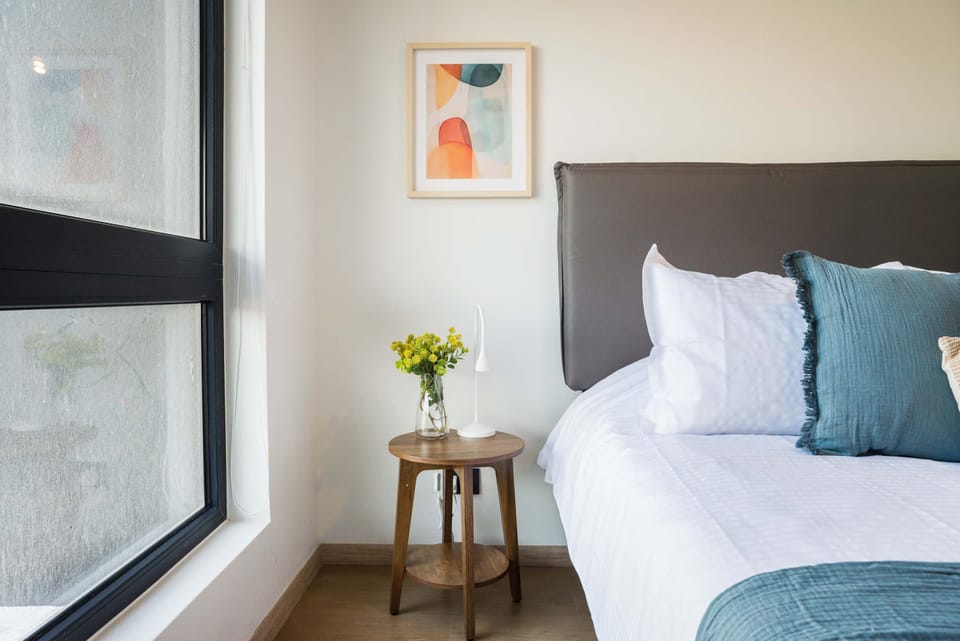Cozy bedroom with large windows, stylish decor, and a serene ambiance perfect for relaxation.