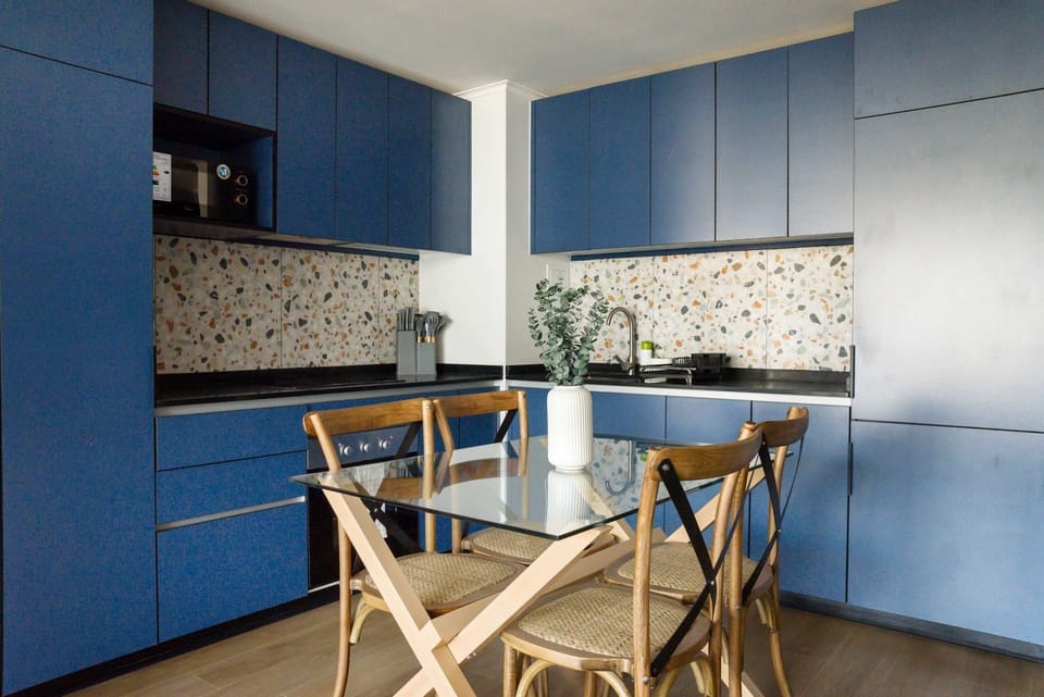 Modern kitchen with blue cabinetry and terrazzo backsplash, perfect for cozy meals and gatherings.