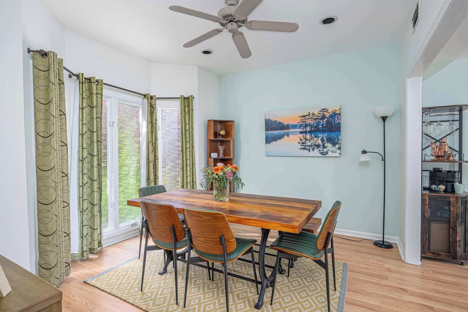 A beautifully styled dining room featuring a wooden table, ambient floor lamp, and a wooden bookshelf tucked into the corner!