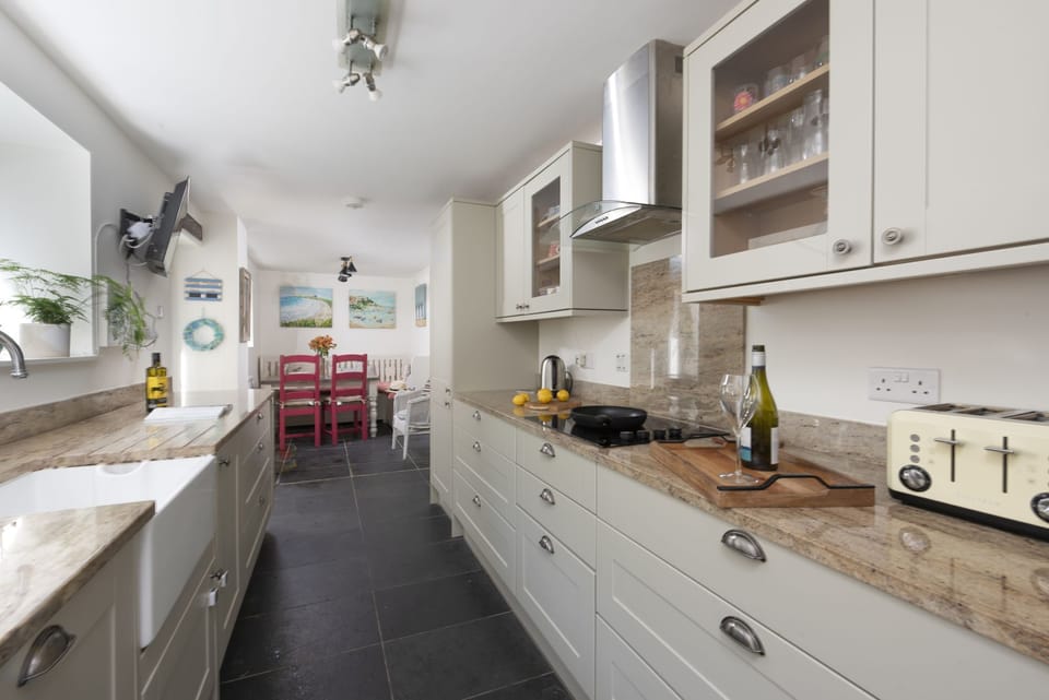 Kitchen with toaster, hob, sink and small dining table - Trevethen Cottage