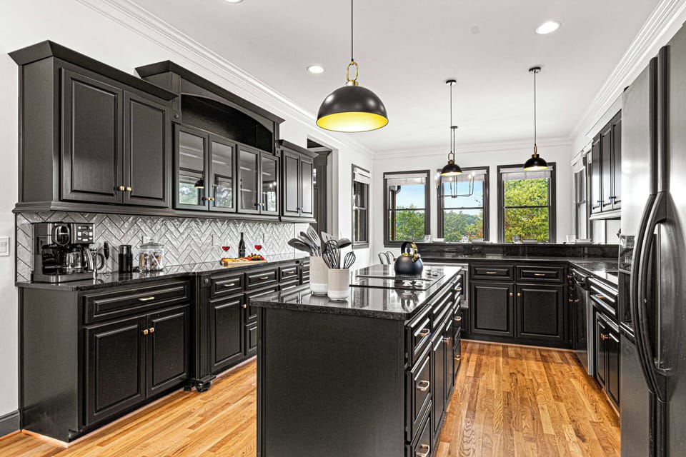 Modern black kitchen with island and stylish pendant lighting.