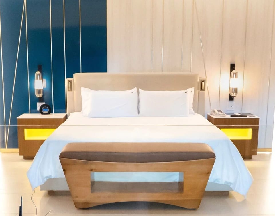 Sink into crisp linens beneath warm, designer bedside lighting.