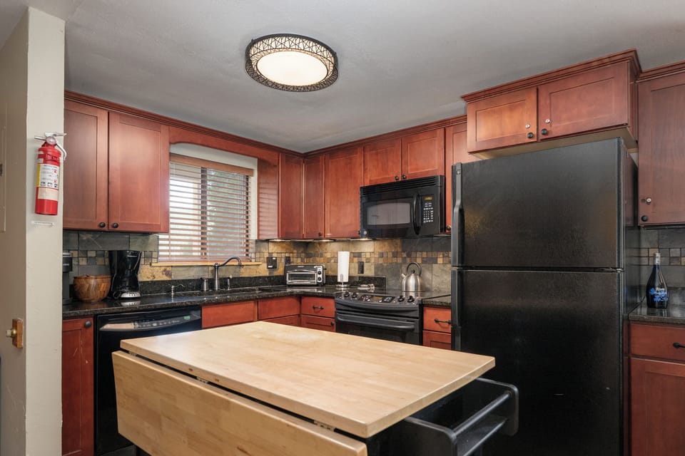 Your fully equipped kitchen features warm wood cabinetry, granite counters, and modern appliances for creating memorable meals during your stay.