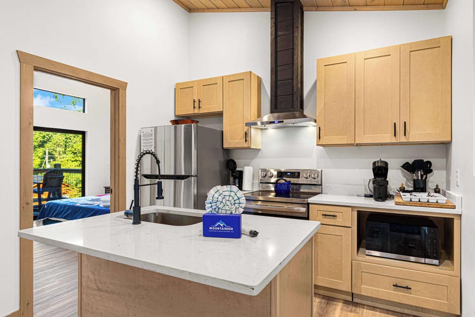 Modern kitchen with light wood cabinets and a large island overlooking the adjacent room.