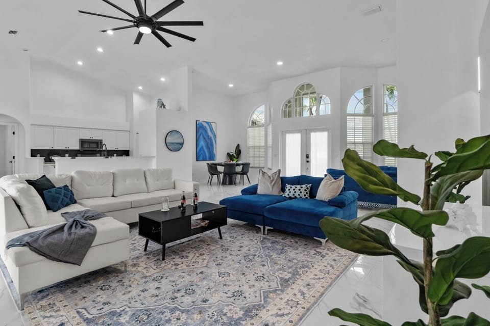 Light-filled open-concept living with soaring ceilings, chic slat‑wood feature wall, modern fixtures, and gleaming marble floors—ideal for guests seeking modern comfort.