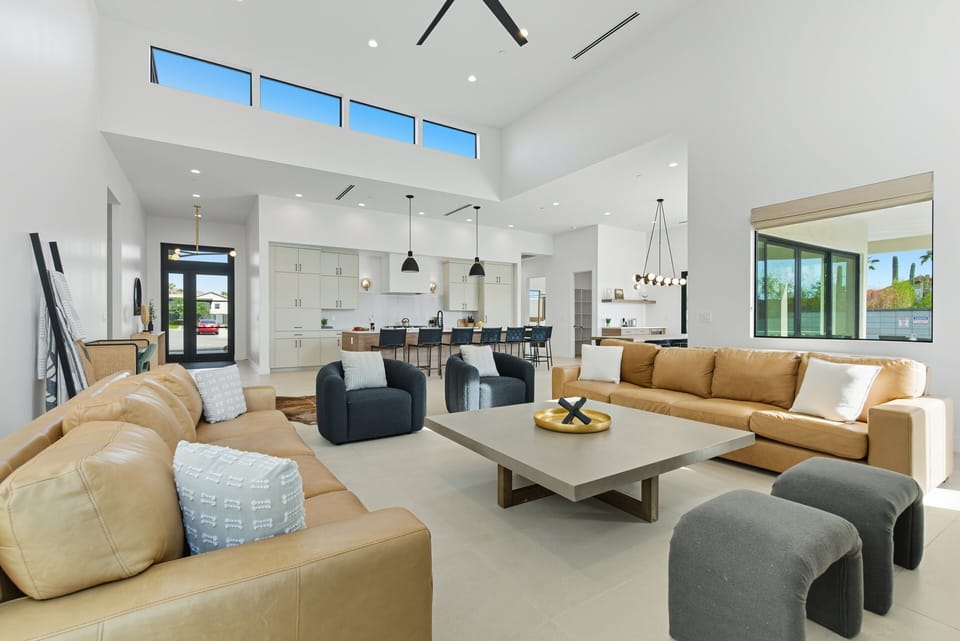 Grand living space featuring sky-high ceilings, an electric fireplace, and a smart TV complete with modern designer furnishings.