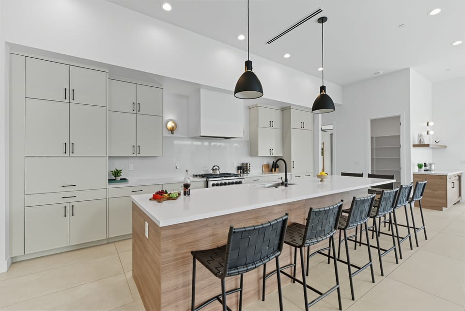 Fully equipped kitchen featuring a large kitchen island offering an abundance of counter space with bar seating, high-end stainless steel appliances, and stocked with all culinary essentials.
