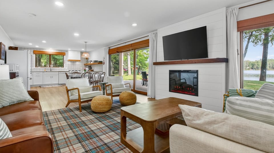Cozy up in the bright, open living room with comfortable seating, fireplace, Roku TV, and big windows that frame the lake.