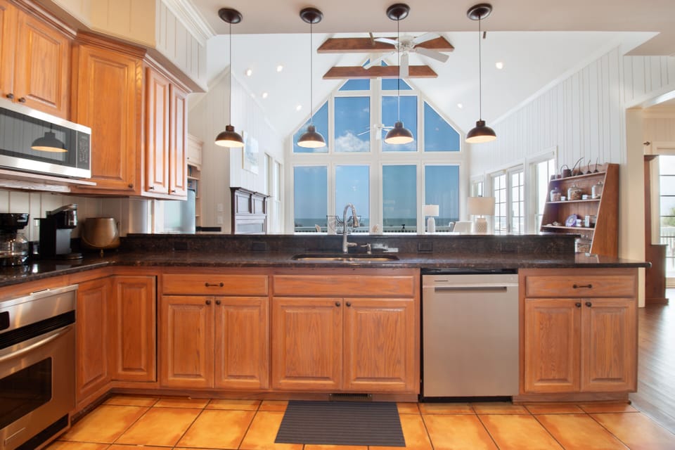 Step into your fully equipped kitchen with stunning floor-to-ceiling windows framing serene ocean views. Cook, gather, and soak in the coastal beauty from this bright, inviting heart of your vacation home.