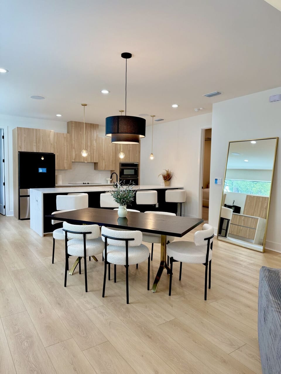 Modern dining area with seating for six, stylish lighting, and open access to the kitchen island for effortless meals and gatherings