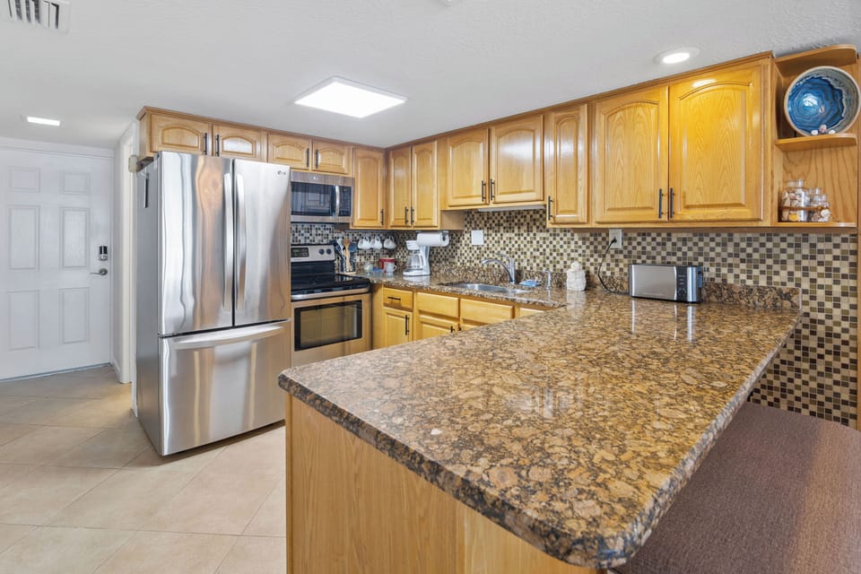 Cook up your favorite beachside meals in this spacious kitchen featuring granite countertops, stainless steel appliances, and warm wood cabinetry for a true coastal comfort feel.