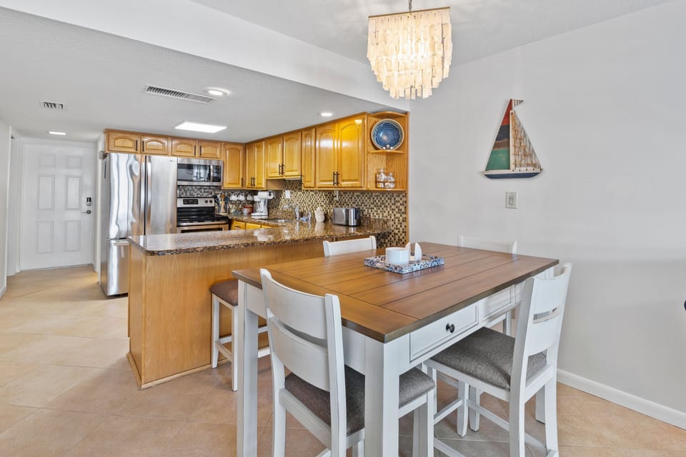 Enjoy a bright beach-style kitchen with stainless steel appliances, warm wood cabinetry, and a cozy dining area—perfect for sharing seaside meals after a day on the shore.