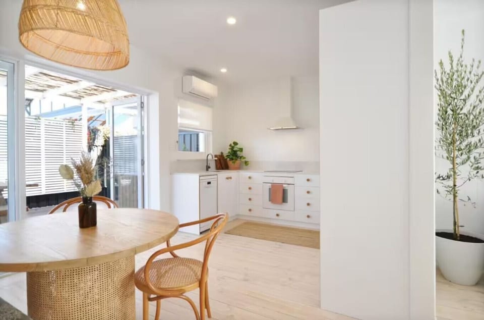 A peek from the kitchen reveals your laid-back dining setup, bathed in natural light.