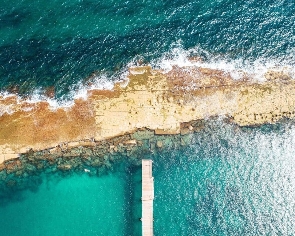 Admire the natural rockpools and clear teal water shaping the rugged shoreline.